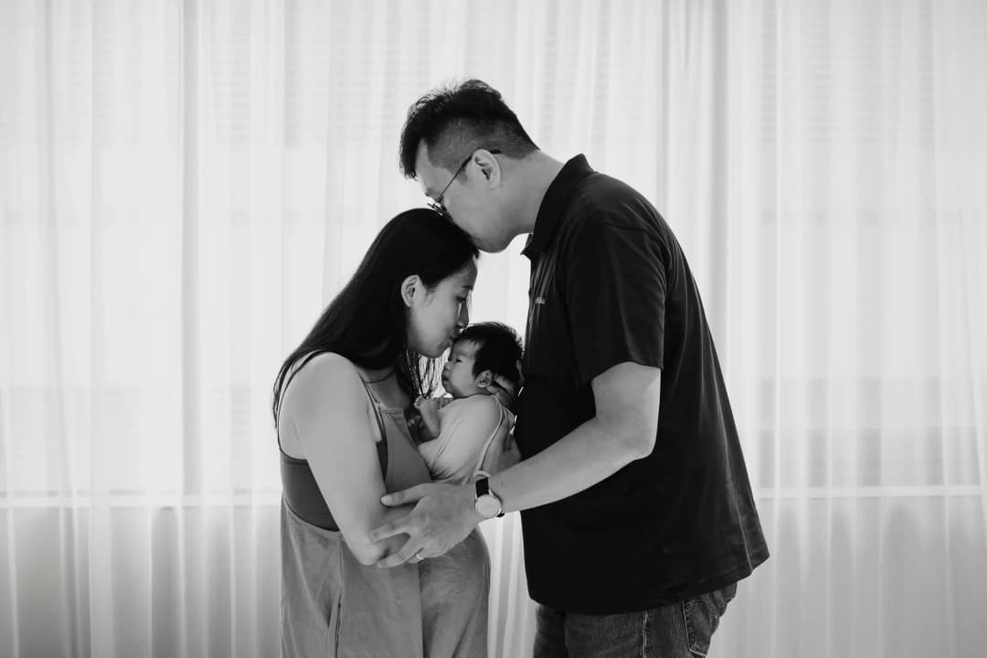 Newborn and parents together in a black-and-white family portrait